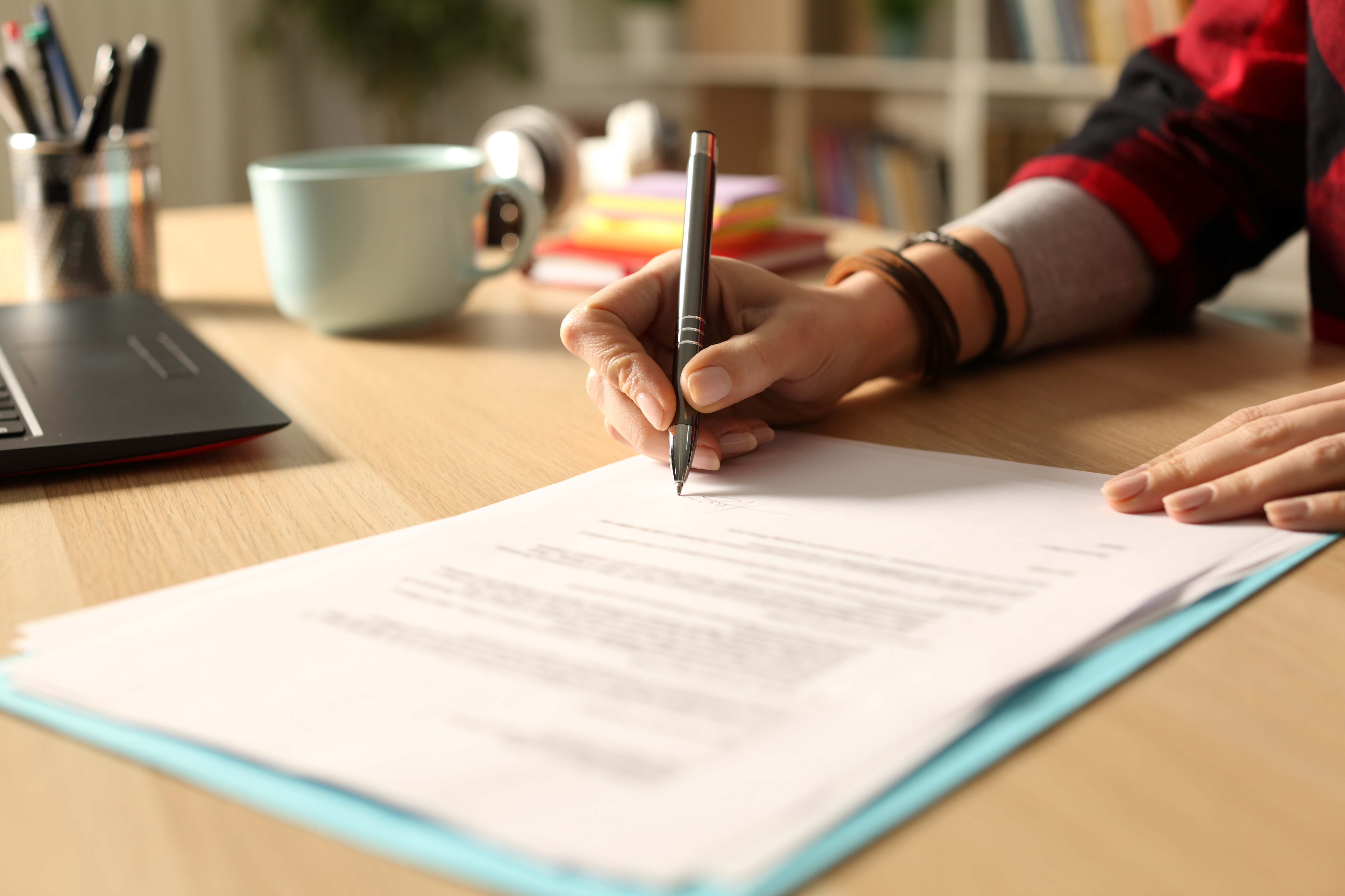 hand signing a document with a pen. Image Credit: AdobeStock_341214580