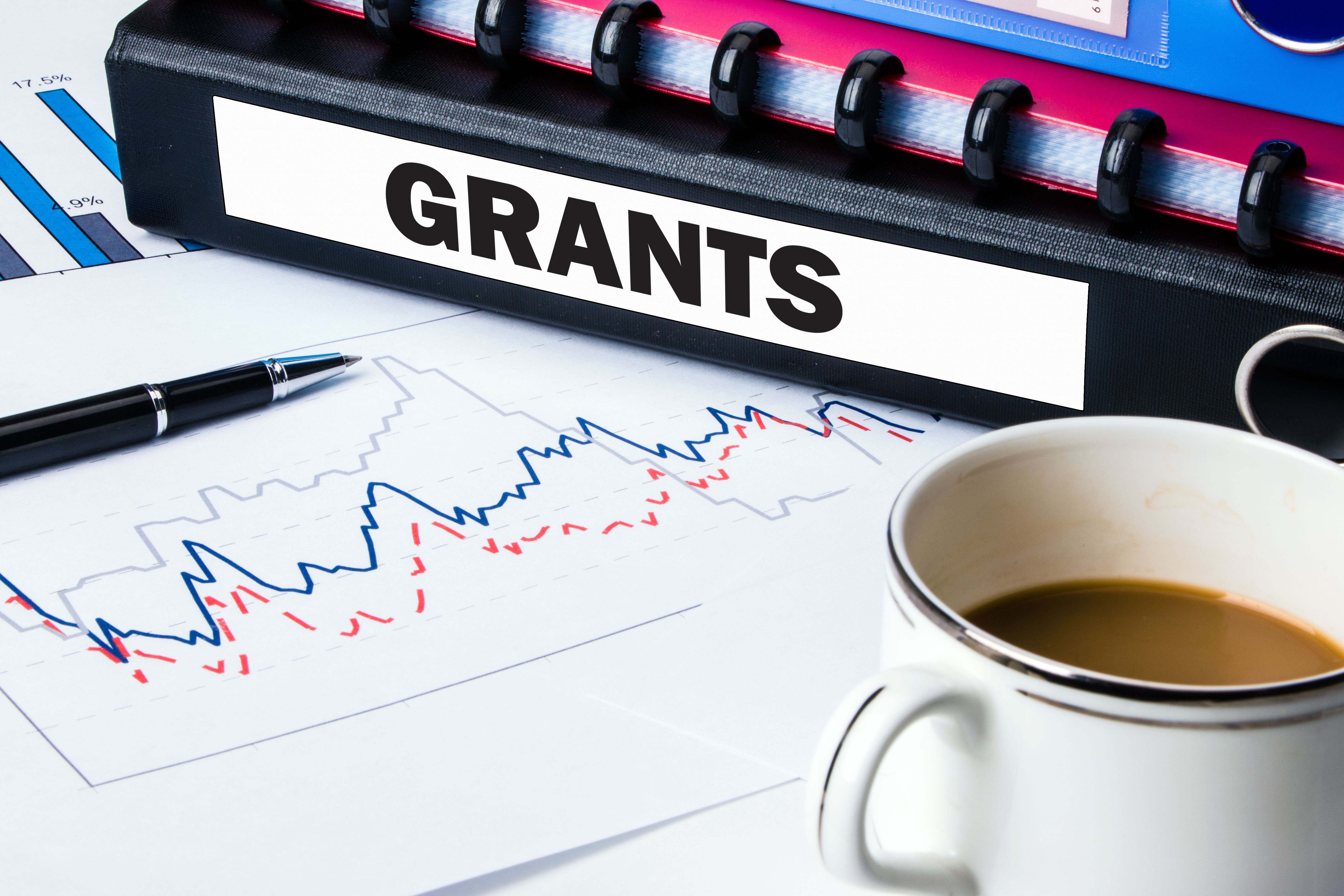 binder labeled 'GRANTS' resting on top of paper with line graph. Image Credit: AdobeStock_79158255